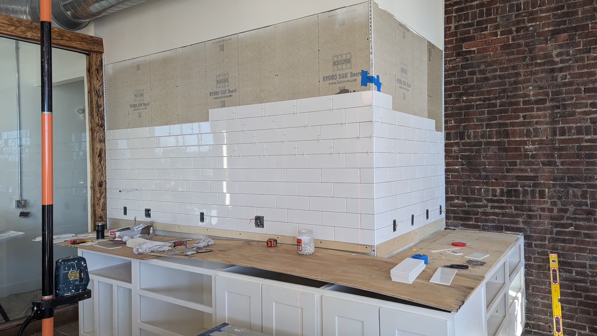 White subway tile being installed over waterproof backer board on a cafe wall in Portland, Maine