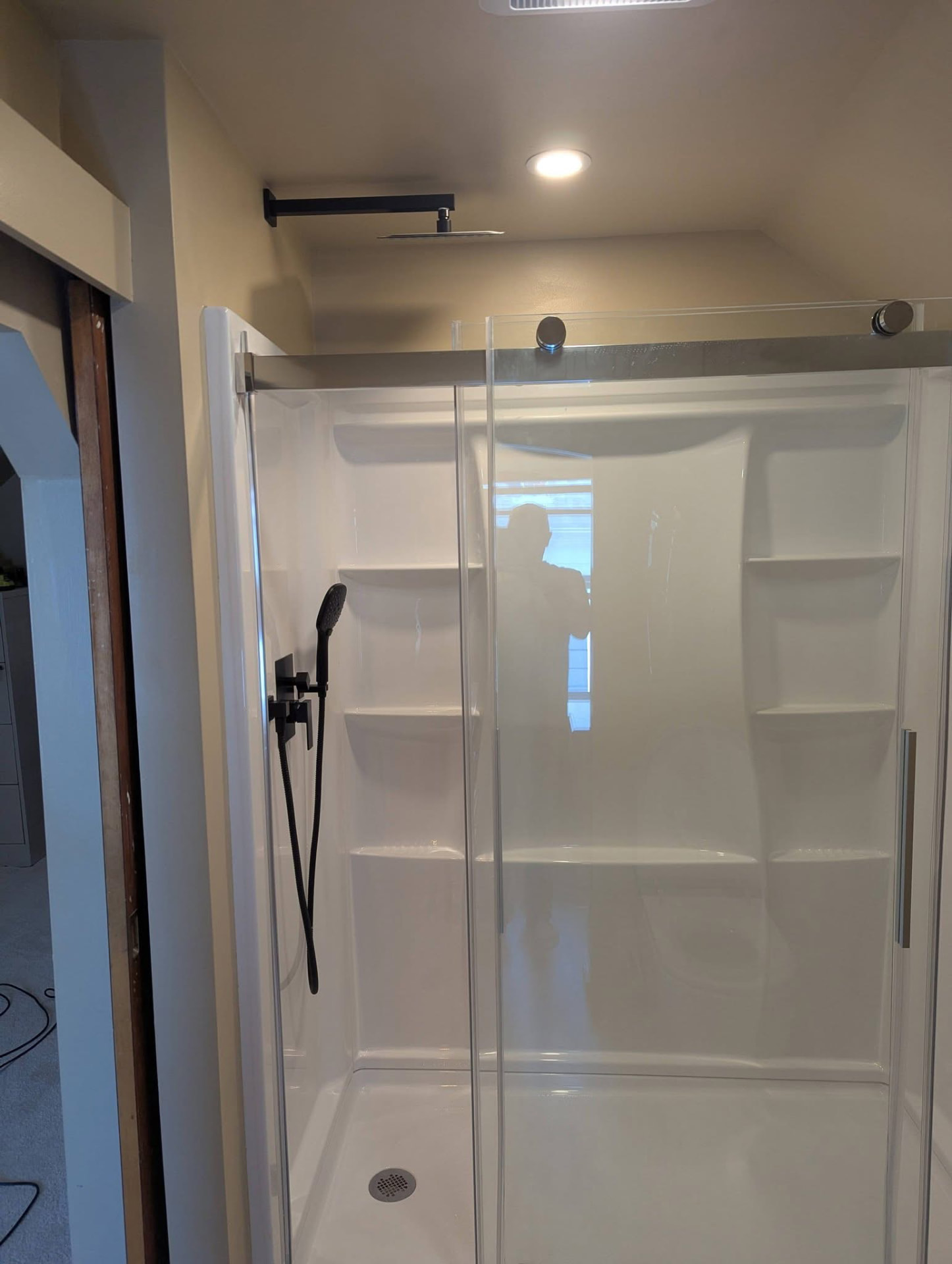 New walk-in shower with glass doors, shelving, and matte black fixtures after remodel in Portland, Maine