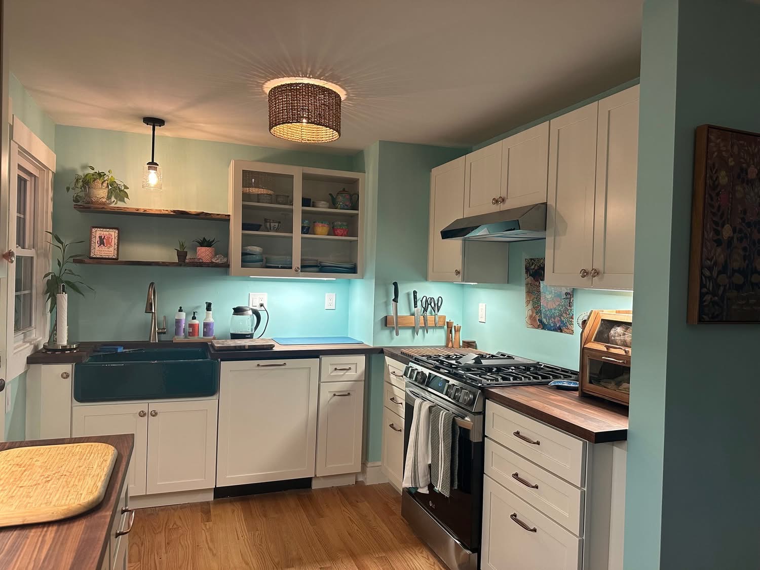 Renovated kitchen with white shaker cabinets, butcher block counters, and teal accent wall after remodel in Portland, Maine