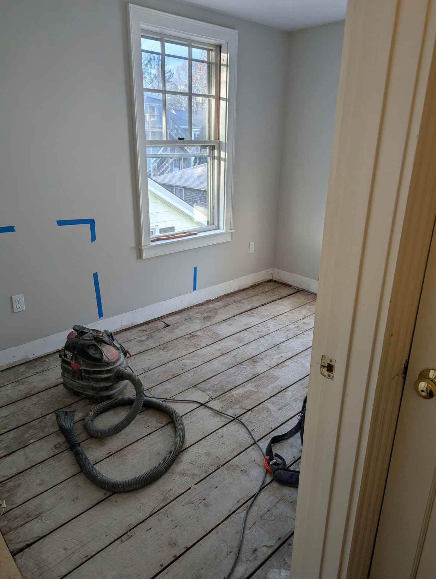 Bare room with worn wood floor before laundry room remodel in Portland, Maine