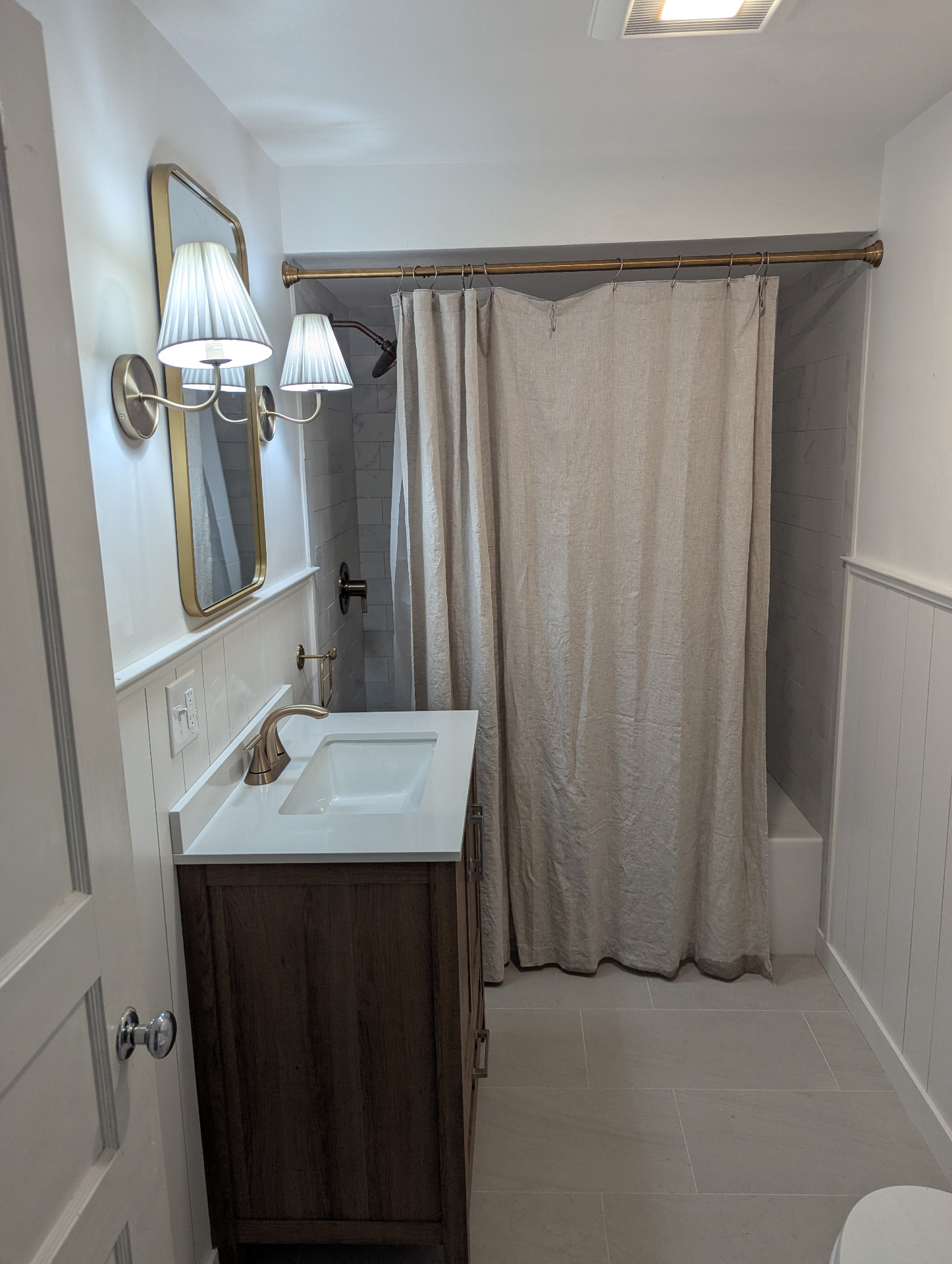 New wood bathroom vanity with white quartz top, brass faucet, and framed mirror in Portland, Maine