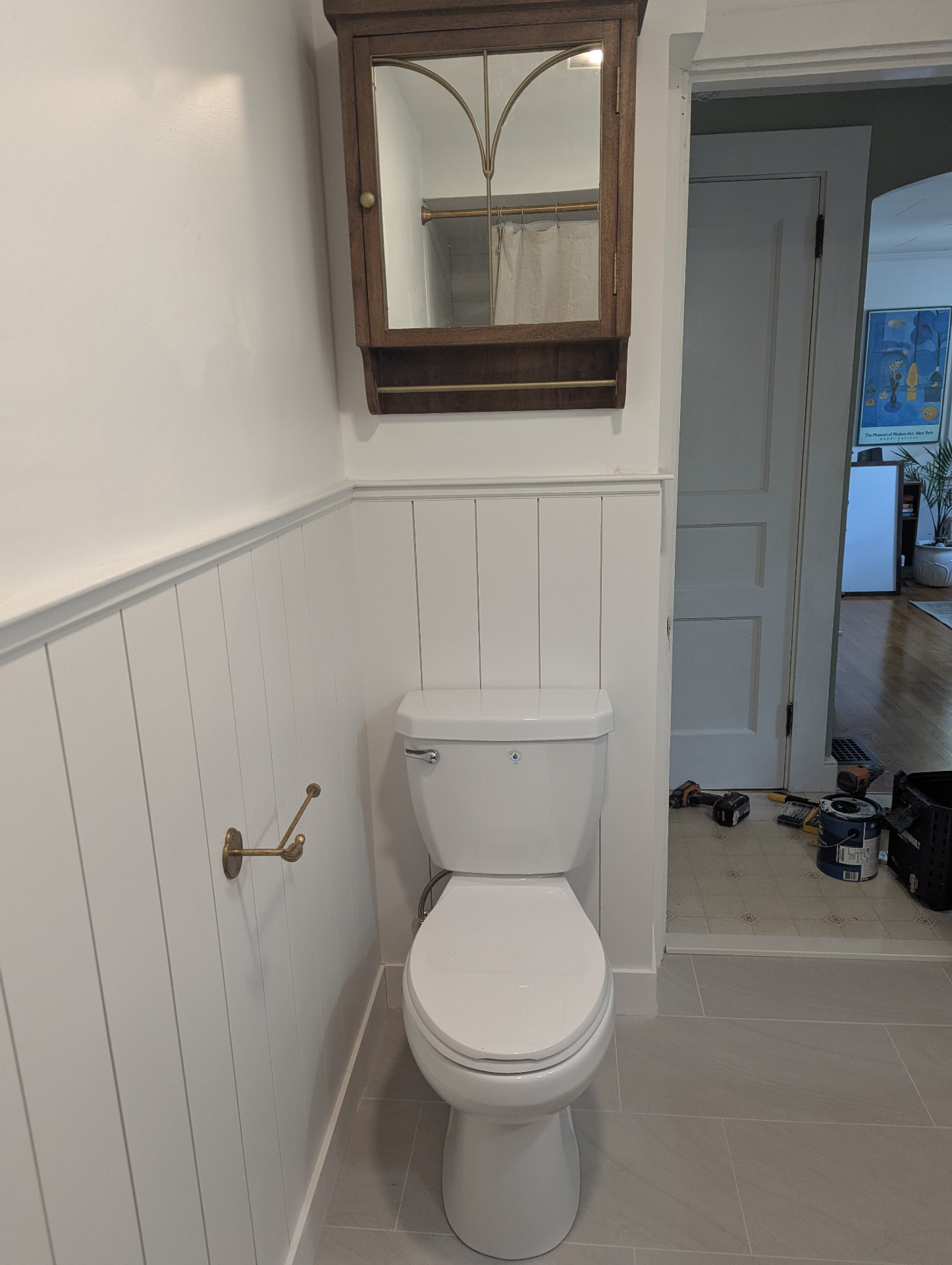 Refreshed toilet nook with white shiplap, brass towel holder, and wood medicine cabinet in Portland, Maine